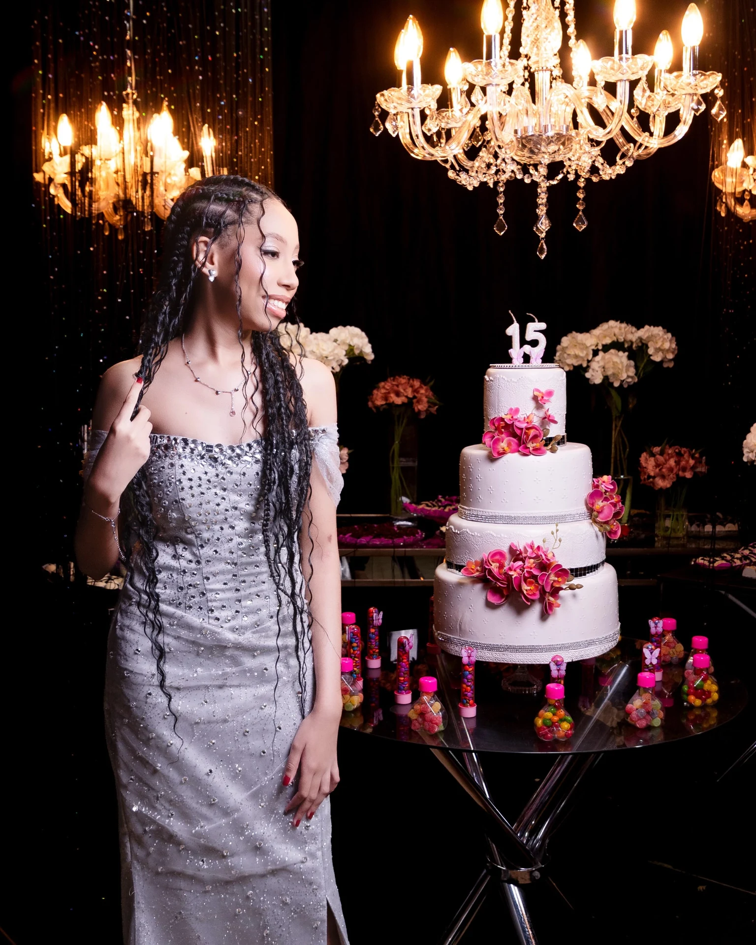 Debutante em festa de 15 anos com vestido prateado e lustre de cristal
